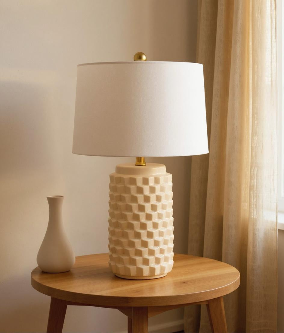 Warm neutral ceramic table lamp with white drum shade on oak side table