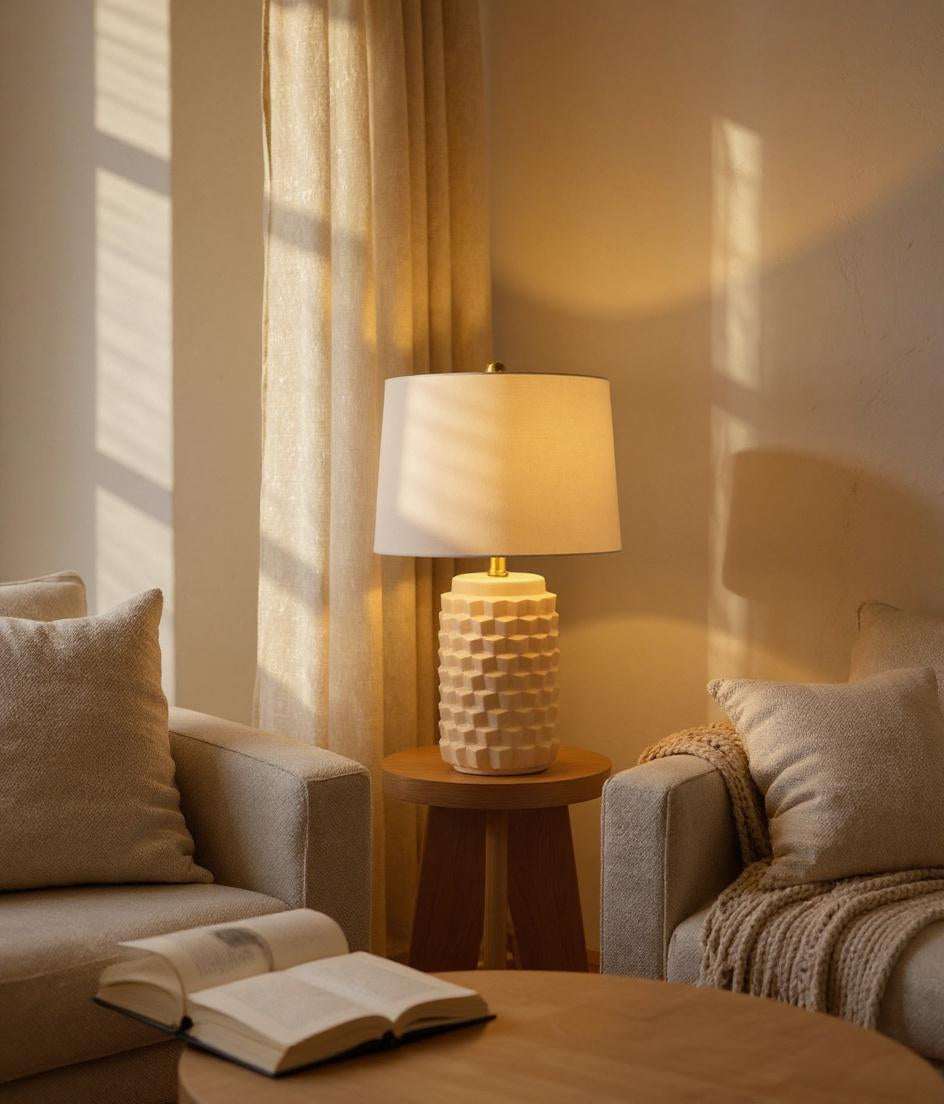 Ceramic table lamp glowing in warm neutral living room with linen textures