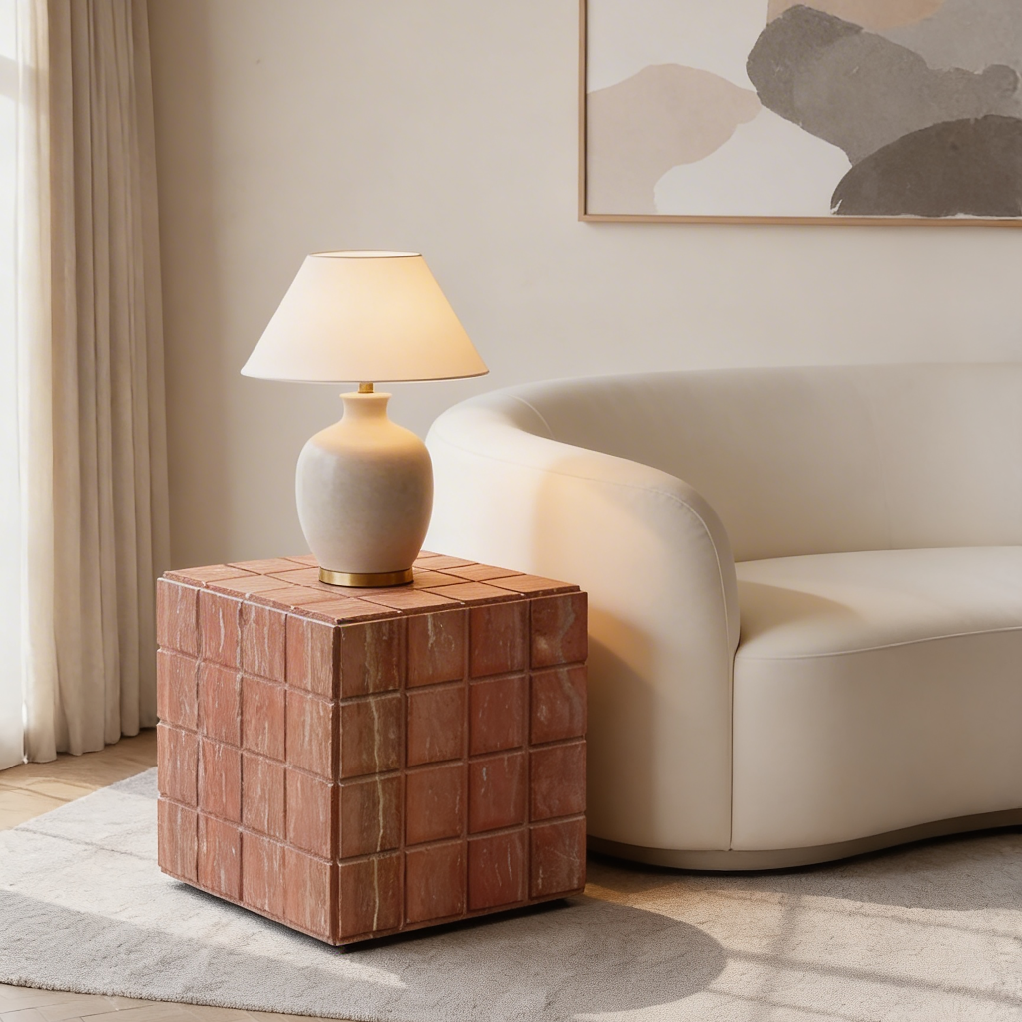 Rounded ceramic table lamp on a terracotta tile side table beside a curved cream sofa, styled in a warm, minimalist living room with soft natural light.